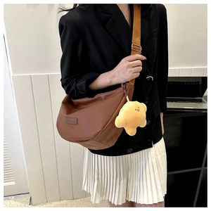 Detail of dark brown crescent crossbody bag with star plush charm on a fashion model