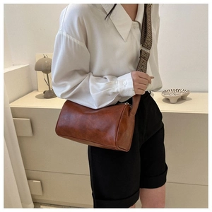 Detail der braunen Leder-Zylindertasche mit böhmischem gewebtem breitem Schultergurt