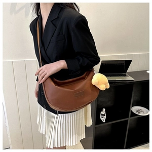 Brown leather hobo bag with yellow chick charm shown on model in modern setting