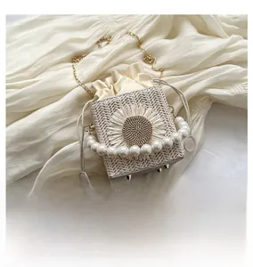 Detail of woven straw mini bag with sunflower embellishment and pearl handle detail