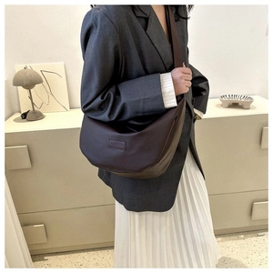 Detail of dark brown dumpling bag with Fashion embossing styled with a grey blazer