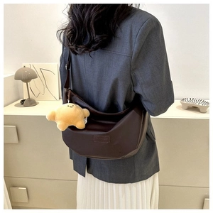 Detail view of a dark brown crescent hobo bag with a star plush charm and matte leather