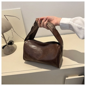 Detailaufnahme braune Zylindertasche aus Leder mit gewebtem Boho-Schultergurt