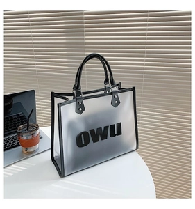 Close-up of semi-transparent PVC tote bag featuring black OWU print and leather handles