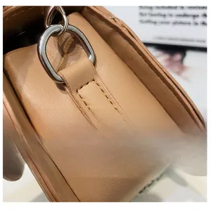 Detailed close-up of premium stitching and silver hardware on a brown handbag