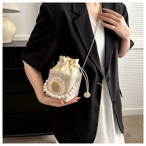Detail of woven bucket bag with sunflower decor and pearl handle on a female model