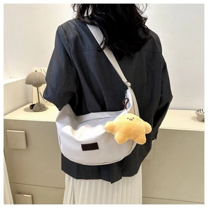 Detail of light grey canvas crescent crossbody bag with yellow star plush charm accessory