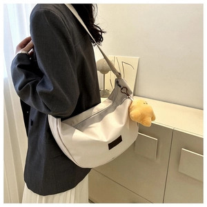 Detailed side view of white crescent bag with star plush charm and adjustable strap