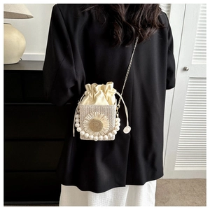 Detail of woven square bag with floral accent, pearl trim, and gold chain strap