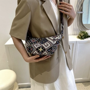 Ethnic geometric woven crescent bag with adjustable strap worn by model in vintage style