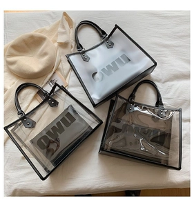 Detail view of transparent PVC tote bags with black handles and OWU lettering logo