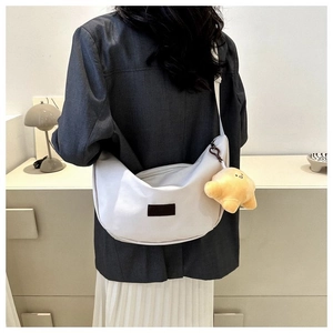 White crescent crossbody bag with cute yellow star plush charm shown on model