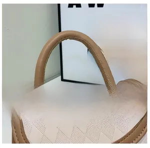 Detail of rhombic quilted crossbody bag featuring stitching on handle and metal rings
