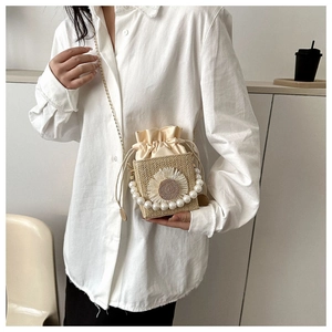 Detail of woven straw square bag with sunflower embroidery and pearl handle strap