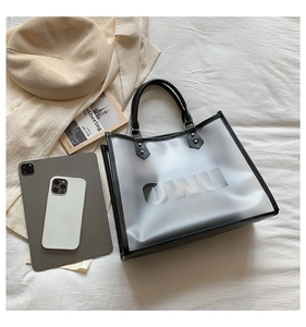 Detailed overhead shot of a translucent tote bag with black leather trim and OWU logo