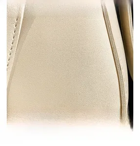 Macro shot of cream bucket bag showing high-quality lychee grain leather and neat stitching