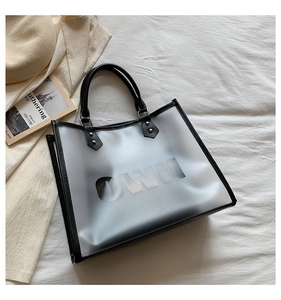 Close-up of translucent frosted tote bag with black leather handles and OWU lettering