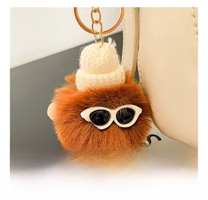 Detail showing a cute brown plush charm with knit hat and sunglasses on a beige handbag