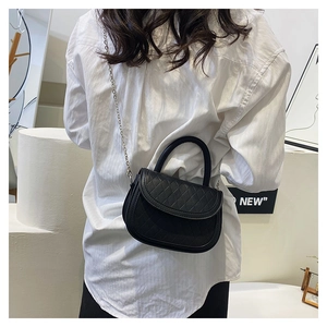 Quilted black crossbody bag with chain strap shown on model in minimalist setting