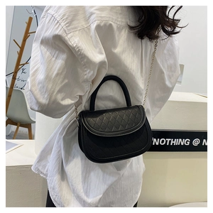 Detail of black quilted leather crossbody bag with metal chain strap and top handle