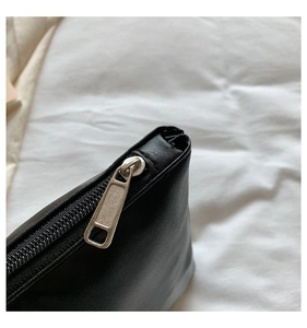 Close-up of matte silver metal zipper and fine leather texture on black tote bag detail