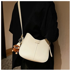 Detail of cream crossbody bucket bag with vertical stitching and plush bear charm