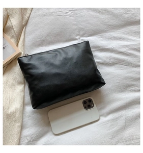 Detail of black leather clutch bag with zipper closure and smartphone for size reference