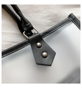 Detailed close-up of translucent PVC tote bag with black leather trim and silver rivets