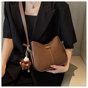 Detailed shot of brown matte leather shoulder bag with FASHION logo and plush charm