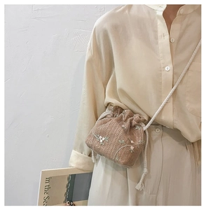 Détail du sac seau en paille avec broderie florale et fermeture à cordon blanc