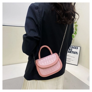 Detailed view of pink quilted saddle bag with gold chain strap worn by a fashion model