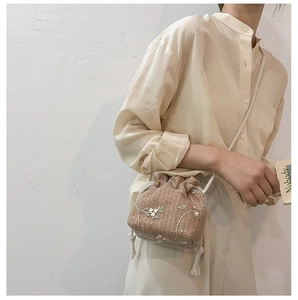 Détail du sac seau en paille tissée à la main avec broderies florales et cordon de serrage