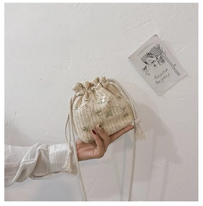Détail d'un mini sac seau en paille tressée avec broderie florale et cordon de serrage