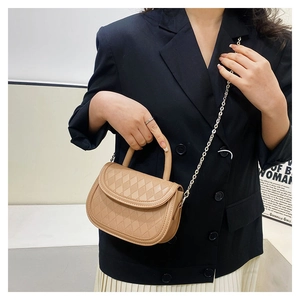Detailed close-up of khaki saddle bag featuring quilted pattern and metal chain strap