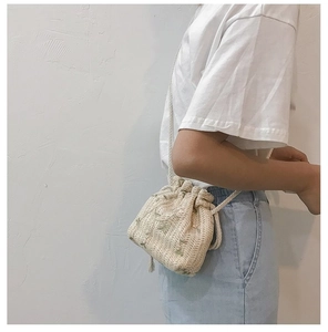 Détail du sac seau en paille avec broderie florale verte et bandoulière cordon