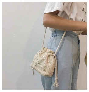 Détail du sac seau en paille tissée avec broderie de feuilles et cordon de serrage