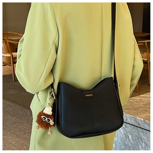 Detail of black leather hobo bag with a cute brown plush charm and fashion buckle