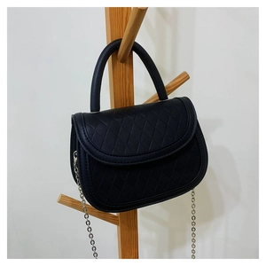 Detail view of black quilted saddle bag with silver chain strap and top handle