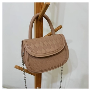 Close-up of khaki saddle bag featuring diamond lattice embossing and metal chain strap