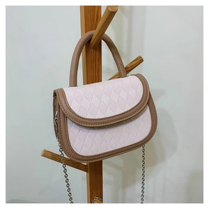 Detail of crossbody bag featuring pink quilted texture and brown leather trim accents