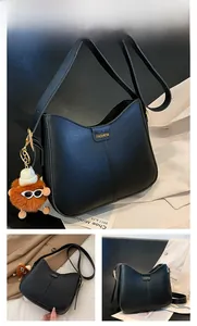 Detail view of black textured leather bucket bag with gold fashion plaque and bear charm