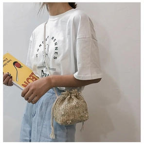 Détail du sac seau en paille avec broderies de fleurs blanches et fermeture à cordon