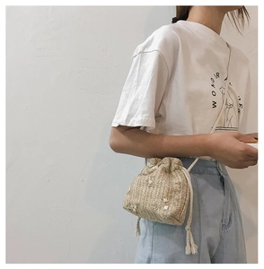 Vue latérale d'un mini sac seau en paille avec broderie florale et fermeture cordon