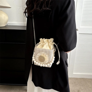 Cream woven crossbody bag with pearl accents and sunflower detail on black blazer