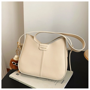 Detail of cream saddle bag with fashion magnetic clasp and cute plush ball charm