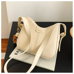 Detail view of cream leather bucket bag with wide strap and brown plush doll pendant