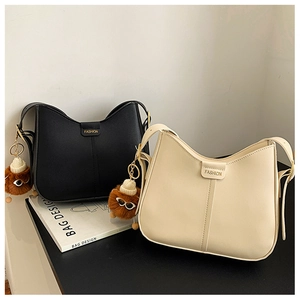 Detailed view of half-moon shoulder bags with unique plush monster charms and gold logos