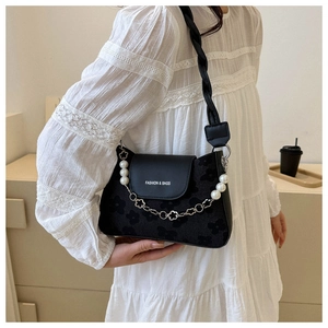 Detail of black matte shoulder bag with pearl and silver floral chain and woven strap