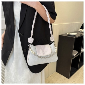 Detail of floral embossed texture and pearl charm chain on a stylish beige handbag
