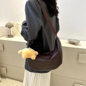 Brown half-moon hobo bag with wide adjustable strap and star plush charm on model